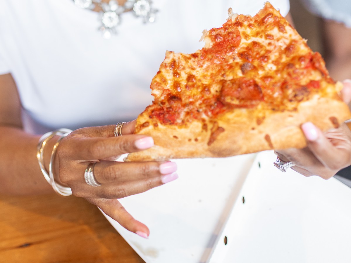 a woman sitting at a table with a slice of pizza