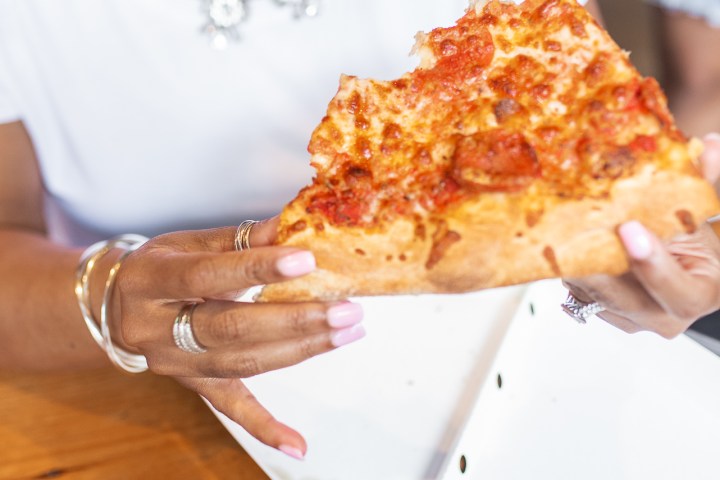a woman sitting at a table with a slice of pizza